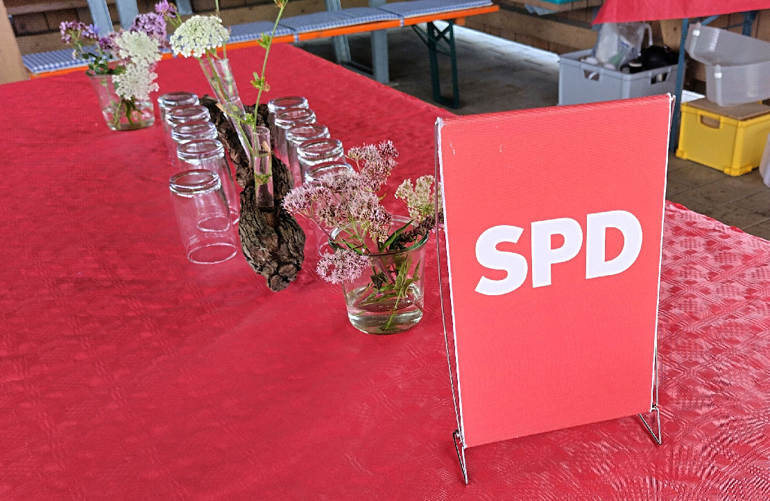 Tisch mit roter Tischdecke, Deko, Gläsern und einem SPD-Tischsegel