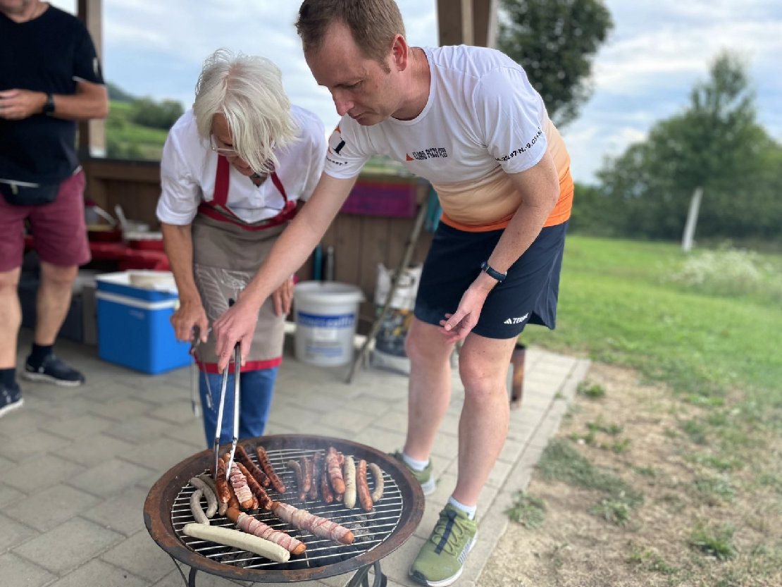 Eine Frau und ein Mann beugen sich über einen Grill, der wirklich sehr niedrig ist.